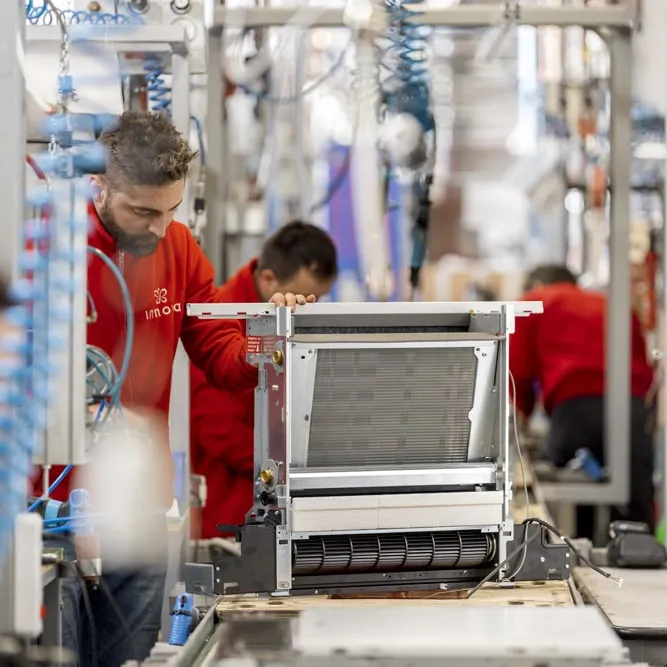 Technicians in red uniforms testing a unit on the production line