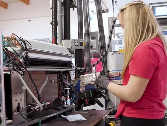 An Innova technician working on a heat-exchanger coil at a test rig in the factory
