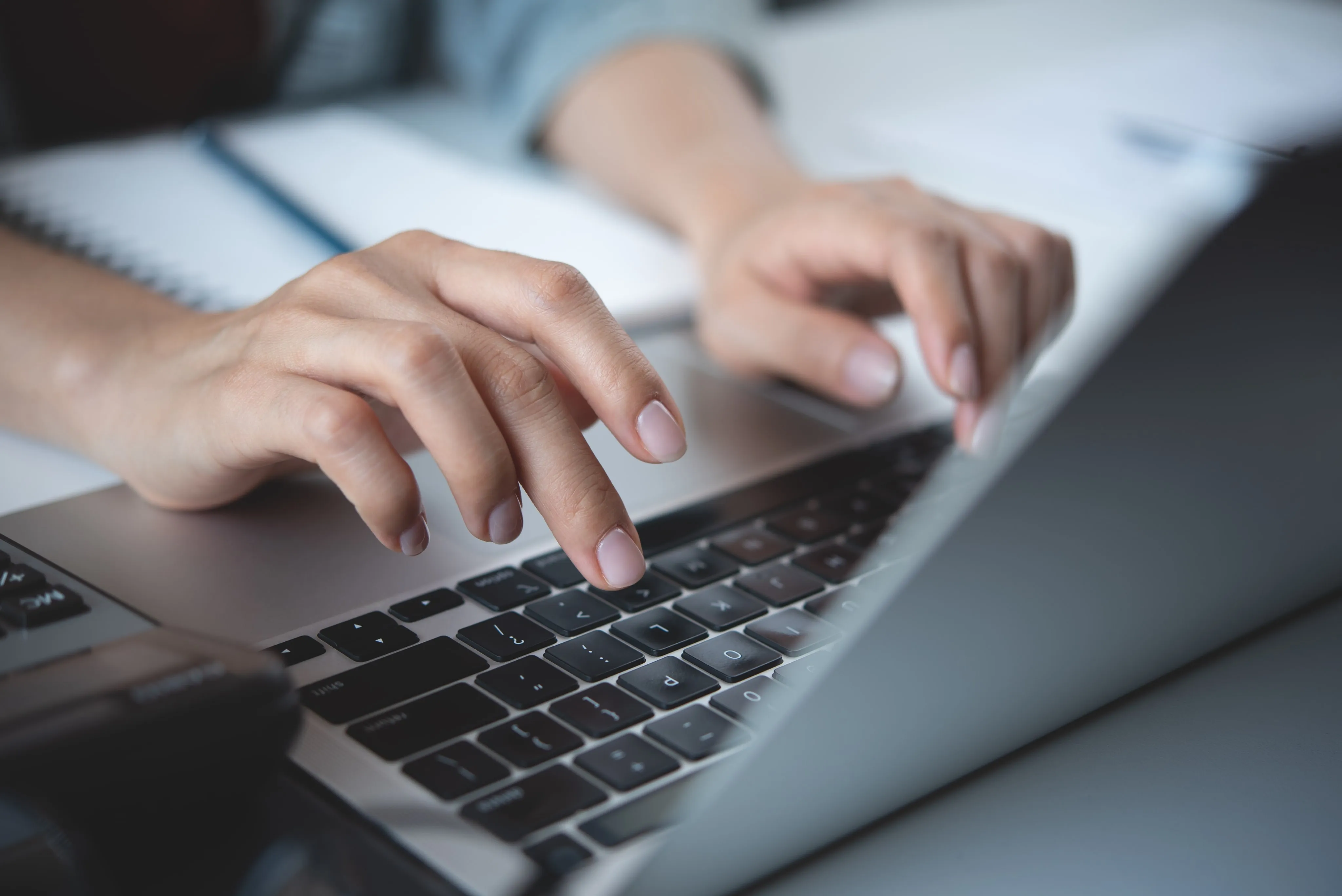 Hands typing on a laptop keyboard