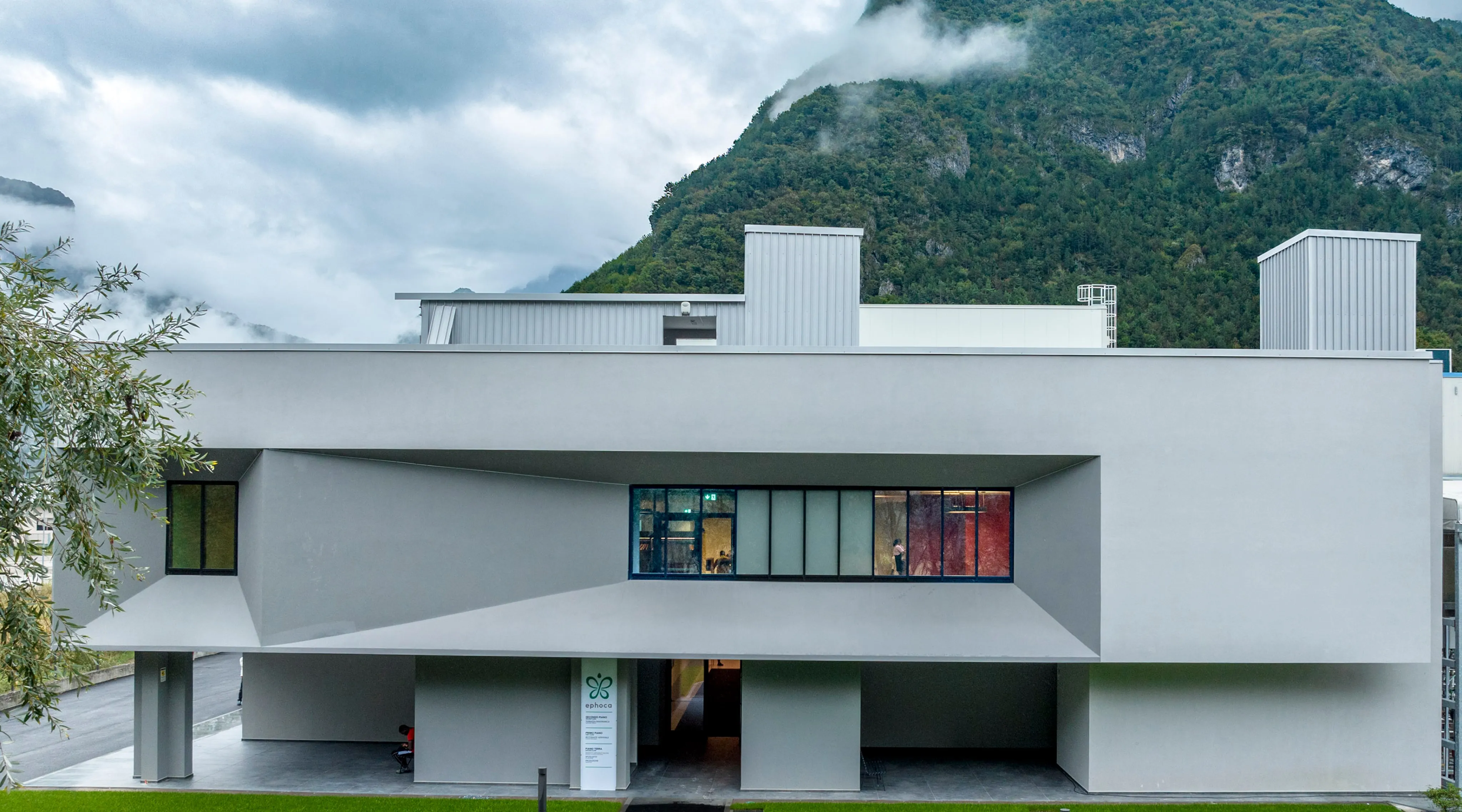 The Innova headquarters, a low white building below a forested mountain